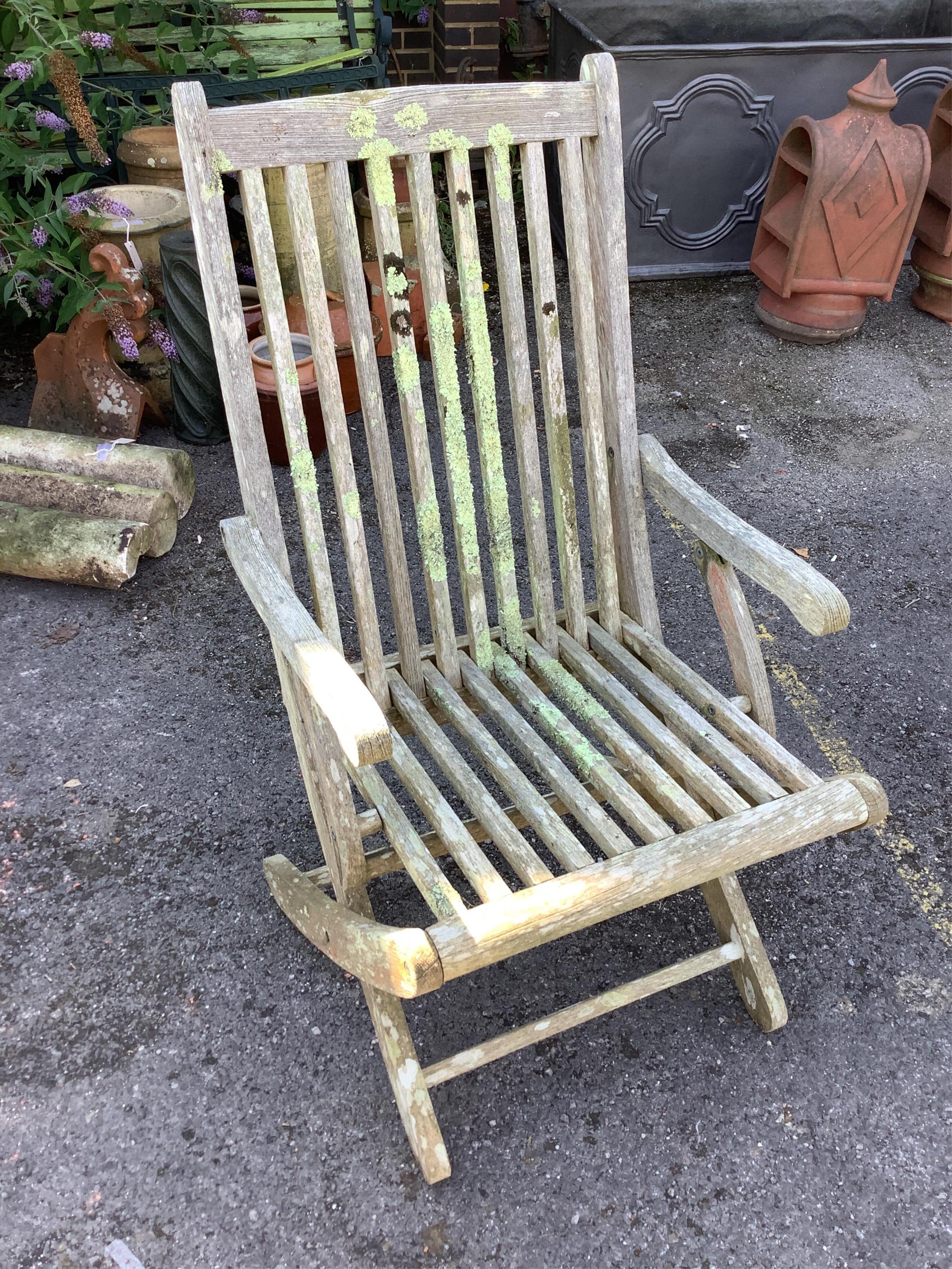 A weathered teak octagonal garden table, width 159cm, height 72cm, together with eight slatted teak folding garden chairs, four with arms. Condition - fair
